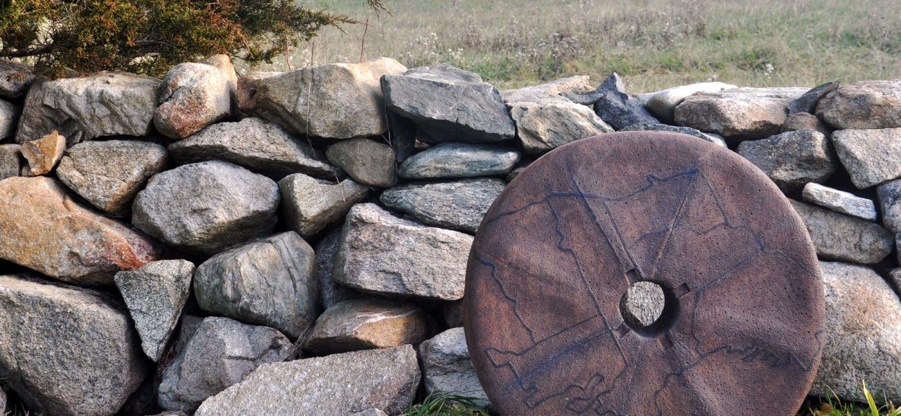 Ashwini Bhat’s Millstone I, 2015, in front of the stonewall rebuilt by Dr. Robert French by the Slocum river, Westport, Massachusetts. Stoneware, 26 in. diameter. Photo by author.